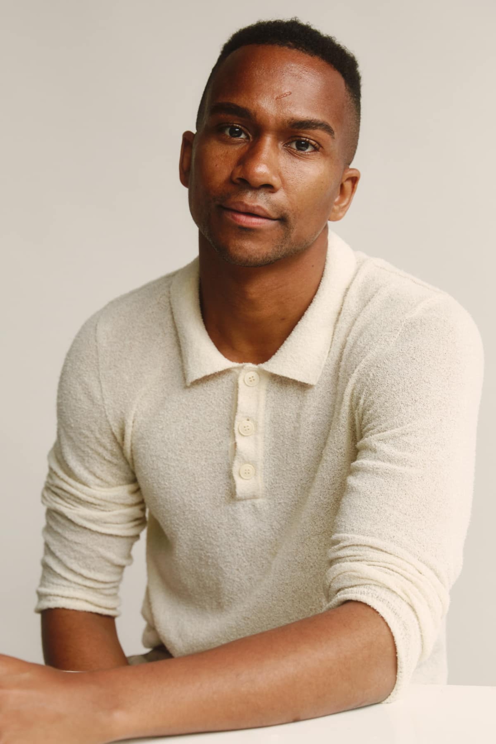 Image of a seated black man in a pale yellow shirt
